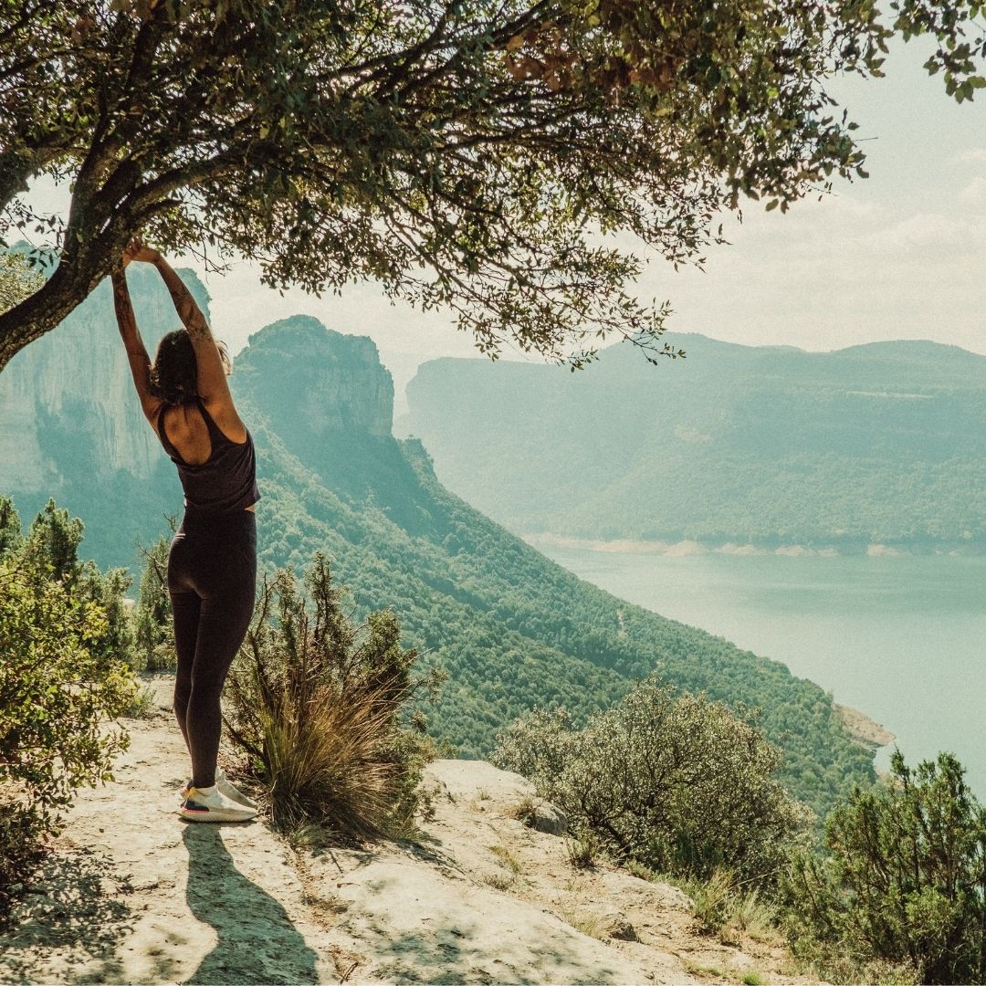 Imagem em tons suaves mostrando o detalhe de mãos alongando calmamente sobre o colo ou o peito, simbolizando o ato de voltar a atenção para si mesmo. A cena transmite uma sensação de acolhimento, presença e segurança, ideal para ilustrar o conceito de consciência corporal na psicoterapia