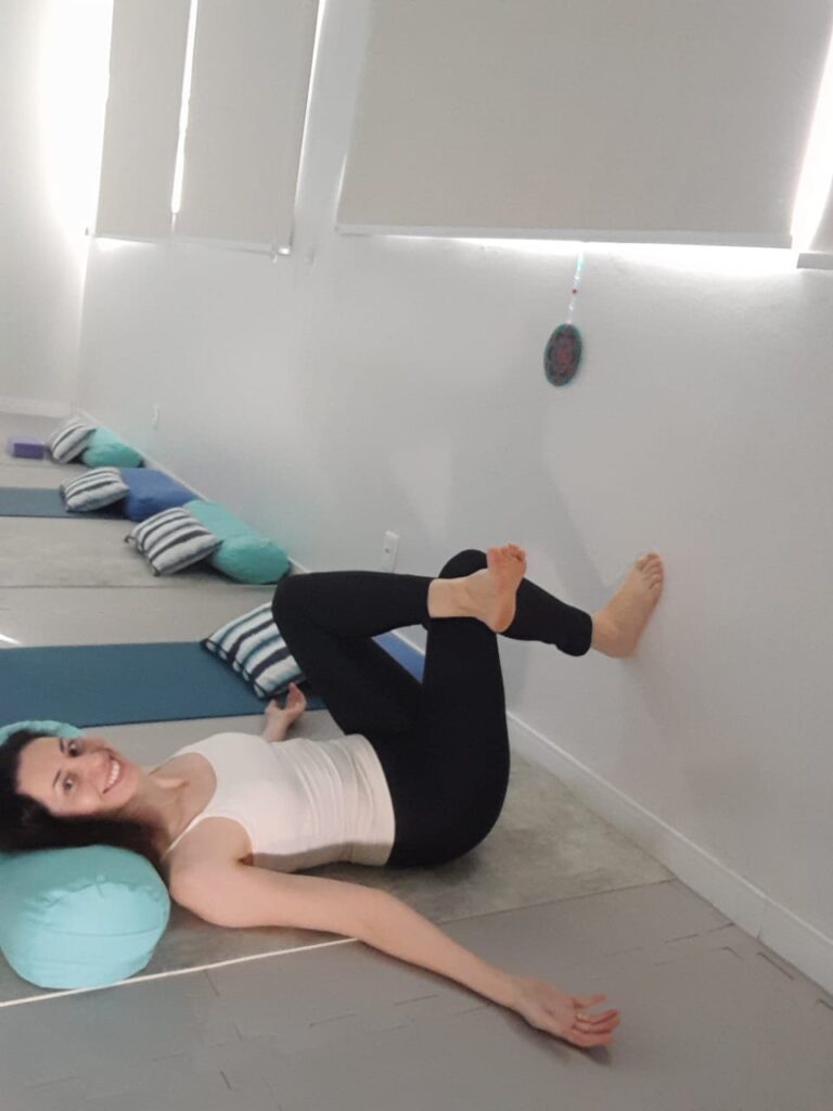Thelma praticando Método Kaiut Yoga com as pernas apoiadas na parede